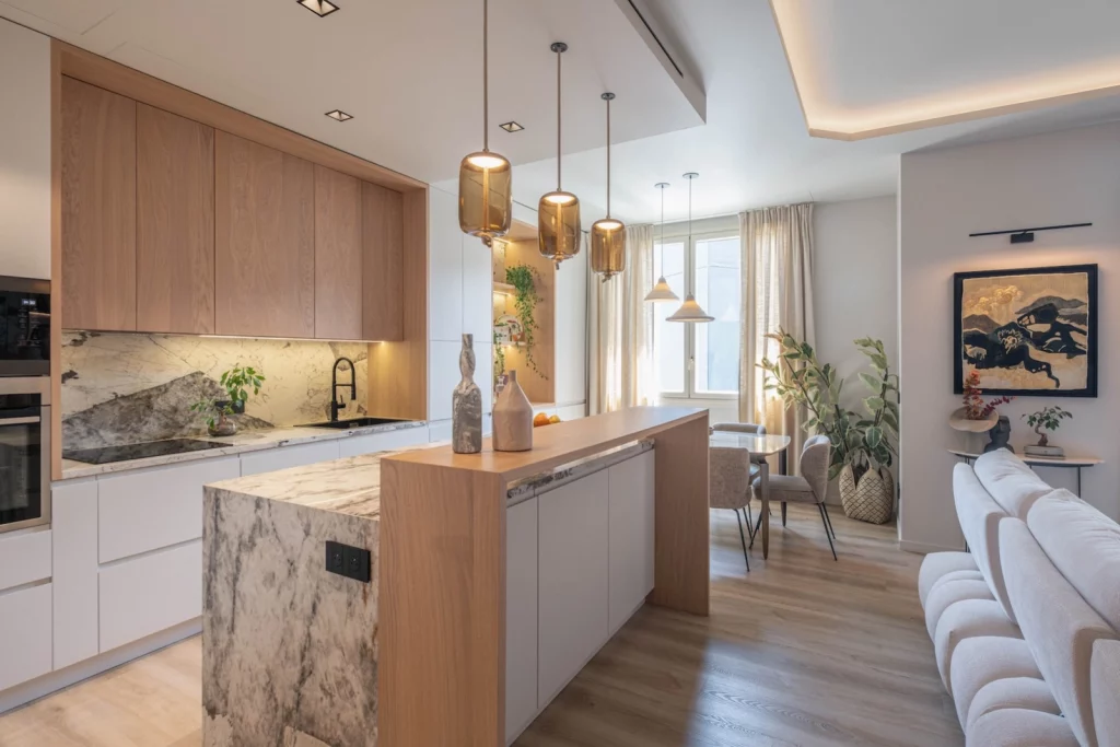 Cuisine contemporaine avec îlot central en marbre, bois naturel et séjour lumineux – Projet L’Azur par Intérieurs à Croquer