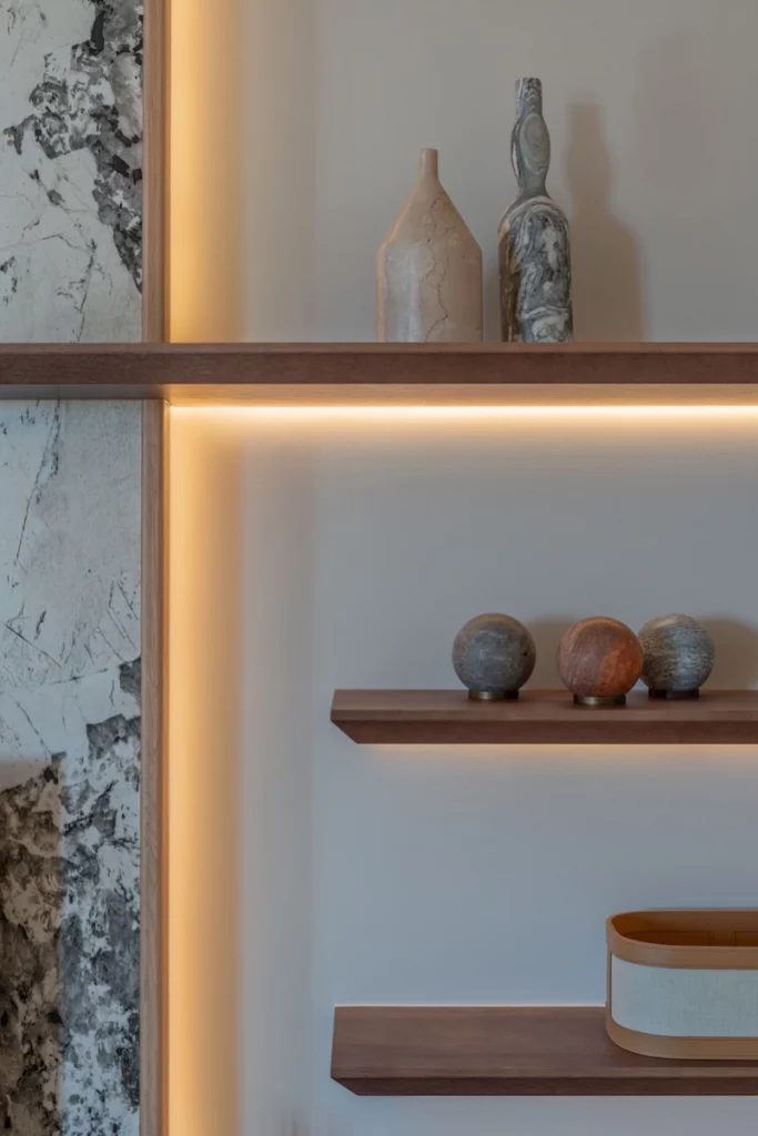 Détail d’étagères en bois avec éclairage intégré et objets décoratifs minéraux – Projet L’Azur par Intérieurs à Croquer